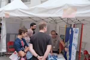 Un animateur présente le planisphère carré à des visiteurs, sous le stand « Les langues dans le monde : visions et perspectives ».