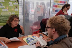 Anne Abeille discute avec un jeune visiteur qui feuillette un livre sur la langue française, à l’atelier Grammaire ludique.