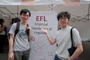 Deux membres de l’équipe posent de part et d’autre du kakémono EFL – Empirical Foundations of Linguistics.